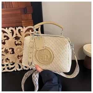 Detaillierte Ansicht der Strohhandtasche mit elegantem Kronenlogo und Schultergurt