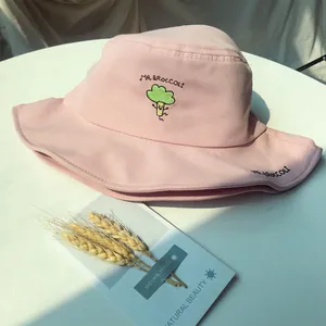 Close-up detail of a pink bucket hat featuring a cute cartoon broccoli embroidery design