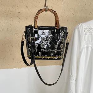 Close-up of black bucket bag featuring retro bamboo handles and intricate beadwork embroidery.