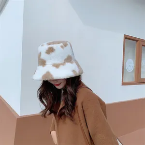 Stylish cow print plush bucket hat for winter, worn by a model in a warm brown coat