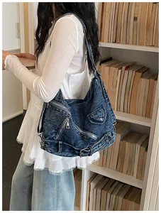 Gros plan d'un sac hobo en jean bleu vintage avec fermetures éclair porté à l'épaule