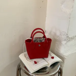 Petit sac à main rouge en cuir grainé avec une doublure intérieure rayée à cordon