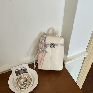Dettaglio di una mini borsa a tracolla crema con ciondolo a stella marina glitterata