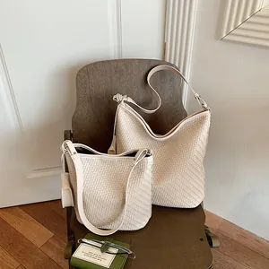 Detailed view of woven beige bucket bags in two sizes for stylish summer commuting.