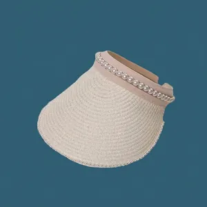 Close-up detail of a women's straw sun visor hat with elegant pearl embellishments