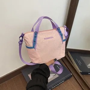 Detailed view of a pink and purple nylon crossbody gym bag held by hand.