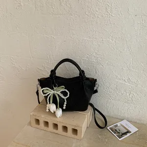 Chic black vintage bucket handbag featuring pearl bow charm and white tulip pendants