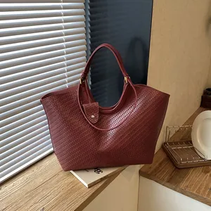 Large burgundy woven tote bag displayed in a stylish indoor lifestyle setting.