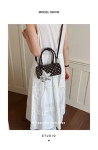 Close-up of model wearing brown polka dot cylinder handbag with star charm detail