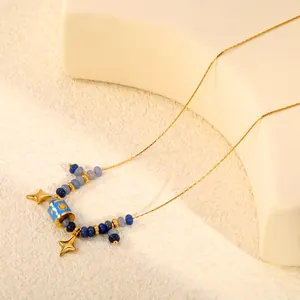 Vue détaillée de l'étoile à quatre branches et des perles émail bleu soleil lune sur un collier.