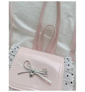 Close-up detail of a pink backpack with polka dot lace trim and silver bow charm