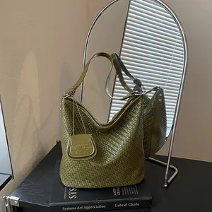 Stylish green woven hobo bucket bag displayed on a book in front of a modern mirror