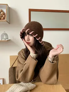 Asiatisches Model trägt eine schicke braun-rosa Strickmütze in einem gemütlichen Café.