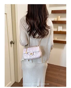 Elegante gewatteerde kettingtas in lichtroze getoond als crossbody op een model