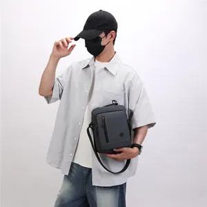 Stylish grey crossbody messenger bag for men shown on a model with a striped shirt