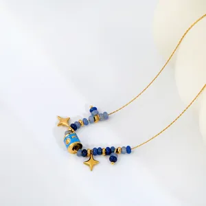 Gros plan d'un collier de perles bleues avec étoiles dorées et motifs soleil et lune.