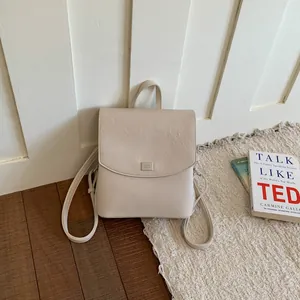Close-up of a cream-white minimalist women's backpack on a textured rug for casual commute