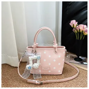 Fashionable pink polka dot handbag featuring a decorative lace musical note charm
