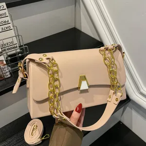 Detail view of an elegant pink small square bag featuring gold chain strap and geometric clasp.