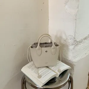 Vue détaillée d'un mini sac à main crème avec une pochette intérieure rayée élégante