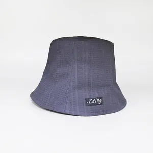 Close-up detail of a dark grey pleated bucket hat for women with a side logo label