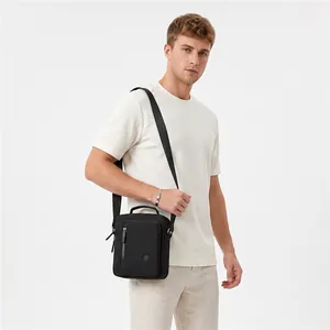Detail of male model wearing a black casual crossbody bag with top handle and zippers