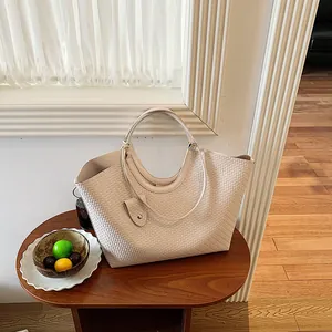 Close-up of a stylish woven tote bag with unique round handles on a wooden table