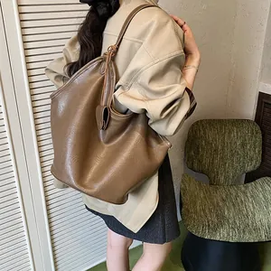 Detailed view of a large brown faux leather slouchy shoulder bag worn on a model