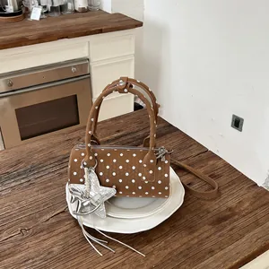 Brown polka dot cylinder handbag with silver star charm on a wooden table