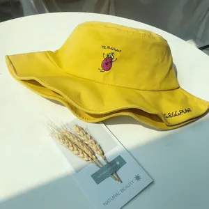 Close-up of yellow cotton bucket hat featuring cute eggplant embroidery
