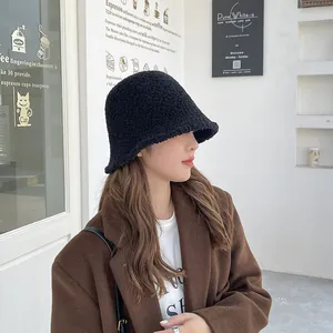 Asian model wearing a thick black lamb wool bucket hat in a stylish cafe setting
