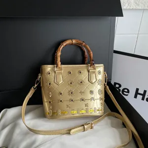 Elegant golden bucket bag featuring a vintage bamboo handle and shiny sun stud details.