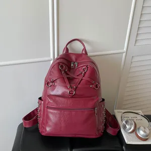 Nahaufnahme eines weinroten Lederrucksacks mit sternförmigem Riemendesign und Nieten