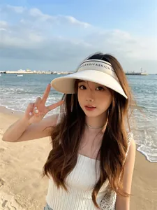 Mannequin asiatique portant un chapeau pare-soleil crème à large bord sur la plage