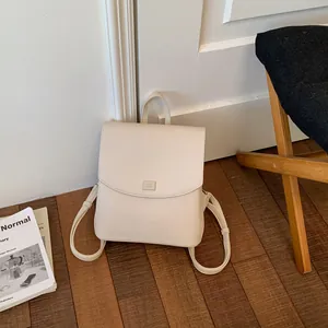 Detail shot of minimalist cream leather backpack in a cozy home lifestyle setting.