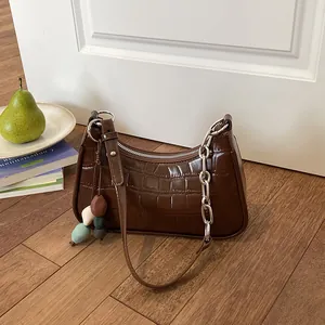 Close-up view of a brown crocodile-embossed dumpling bag with stylish silver chain strap.
