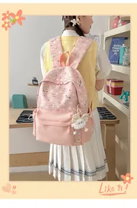 Pink cartoon backpack featuring unicorn print and fluffy white charm in lifestyle setting