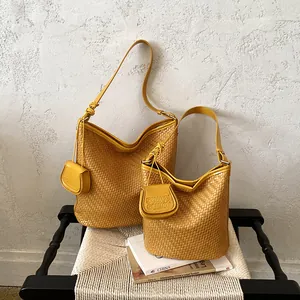 Detail of large and small yellow woven bucket bags on a rustic chair