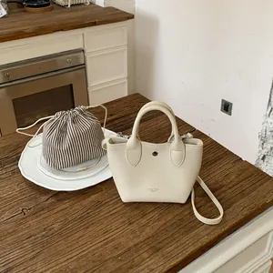 Mini sac à main crème avec pochette intérieure rayée sur une surface en bois rustique