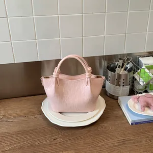Close-up of a pink crinkled leather bucket bag with decorative knot handles