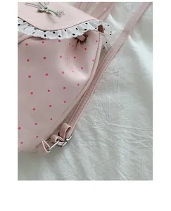 Detailed macro shot of a stylish pink polka dot backpack with white lace ruffle detail.