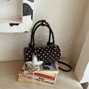 Detail of a brown woven barrel bag with blue polka dots resting on vintage books