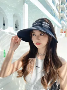Mannequin asiatique portant une visière pare-soleil noire à large bord avec rayures blanches