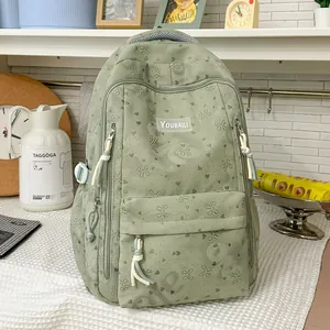 Close-up of a sage green backpack with heart and bow patterns in a lifestyle setting