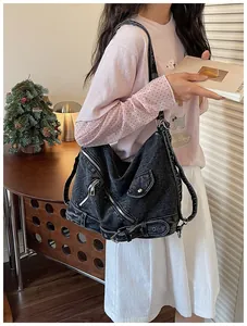 Détail d'un sac à bandoulière en denim noir vintage porté avec une tenue décontractée.