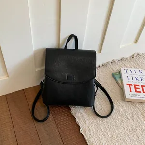 Minimalist black leather backpack for women shown in a cozy indoor lifestyle setting