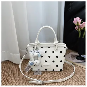 White chic polka dot handbag with black spots and elegant musical note charm detail