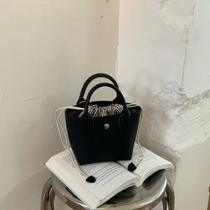 Gros plan d'un mini sac seau rétro noir avec cordon de serrage rayé et doubles poignées