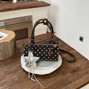 Brown woven cylinder handbag with blue polka dots and silver star charm detail
