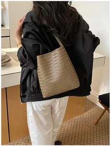Vista detallada del bolso de hombro tipo cubo tejido marrón para mujer, estilo minimal